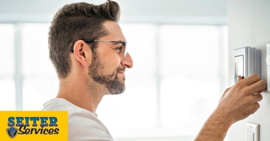 A homeowner adjusting his thermostat.
