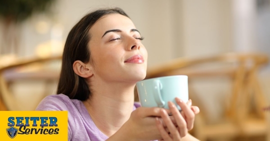 Woman taking deep breath holding a mug.