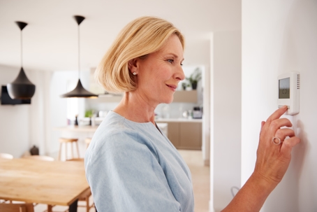 A homeowner adjusting their thermostat.